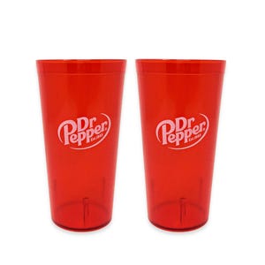 May include: Two identical translucent red plastic tumblers, each featuring the white Dr. Pepper Est. 1885 logo printed on the front. The cups have a tapered cylindrical shape with a smooth finish and a flat base, designed for holding cold beverages.