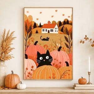 May include: A framed wall art print featuring a whimsical autumn landscape with a white house, rolling hills, and falling leaves. A large black cat with wide eyes sits among several orange pumpkins in the foreground, with a smaller black cat nearby.