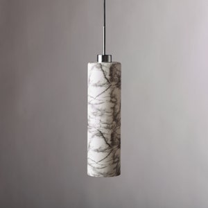 May include: A white marble pendant light with a chrome finish. The light fixture is cylindrical in shape and has a marbled pattern.