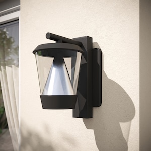 Puede incluir: Aplique de pared exterior negro con una pantalla de vidrio transparente y un reflector plateado. La luz está montada en una pared blanca.
