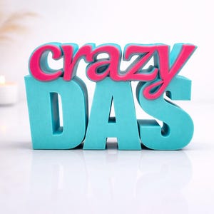 Op de afbeelding: Decoratief bord met de tekst "crazy DAD". Het woord "crazy" is roze en het woord "DAD" is turquoise. Een kleurrijk en leuk decoratie-object, ideaal voor een plank of bureau.