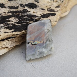 May include: A grey, white and brown labradorite gemstone with iridescent flashes of colour. The gemstone is irregularly shaped and has a rough, natural finish.