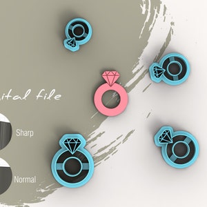 May include: A set of five cookie cutters in the shape of a ring with a diamond. The cutters are in various colors, including pink, blue, and black. The cutters are on a white background with a gray brushstroke design.