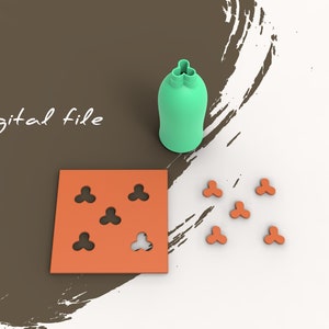 Puede incluir: Un archivo digital para un molde impreso en 3D con cinco recortes en forma de trébol. El molde es naranja y los recortes son negros. Hay cinco piezas separadas en forma de trébol en la imagen, también naranja con recortes negros.
