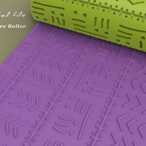 May include: A green texture roller with a geometric pattern. The roller is rolling over a purple surface with the same pattern.