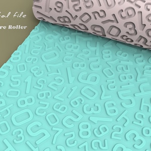 Puede incluir: Un rodillo de textura azul turquesa con un patrón de números en relieve. El rodillo está parcialmente desenrollado, revelando una versión gris claro del mismo patrón.