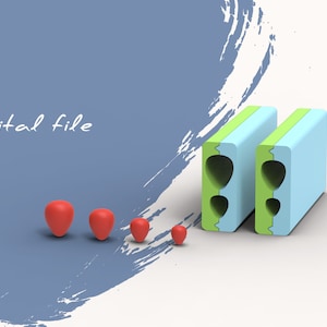 May include: A digital file image showing two green and blue blocks with a hole in the middle. There are four red spheres of different sizes in front of the blocks.