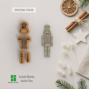 May include: A collection of beige and orange nutcracker cookie cutters and a finished nutcracker. The image includes the text "DIGITAL FILES" and "Include Bambu studio Files". The cutters are in pieces, ready for use.