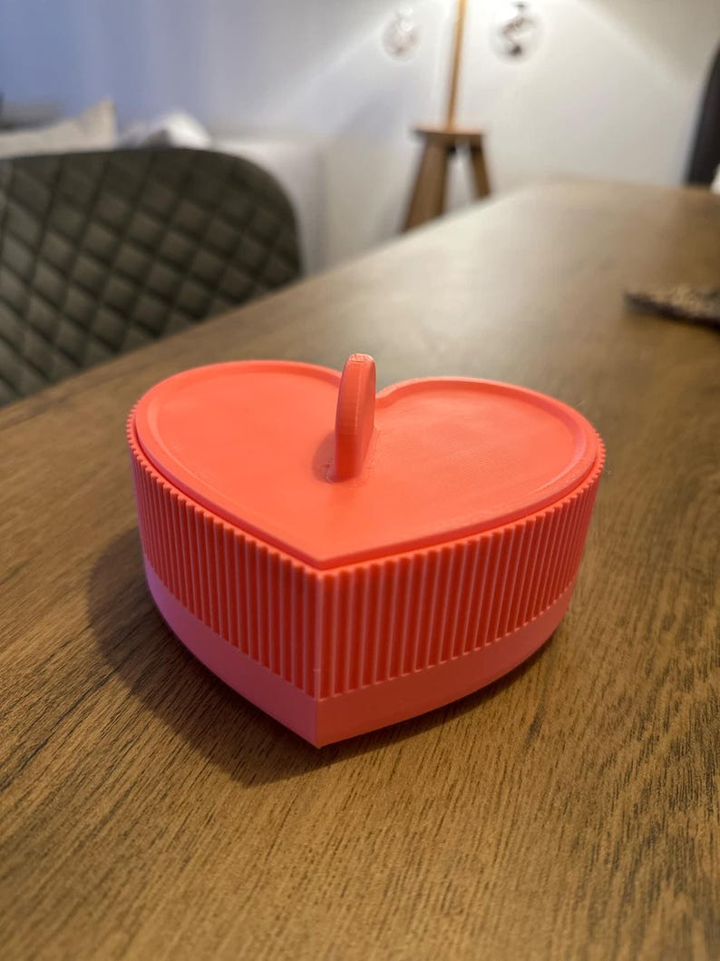May include: A bright pink heart-shaped trinket box with a ribbed texture and a small handle on top.