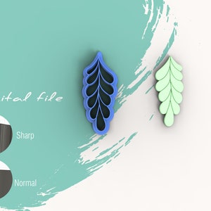 Op de afbeelding: Een blauwe, plastic blaadjesvormige koekjesuitsteker met een gedetailleerd ontwerp. De uitsteker wordt getoond naast een groene versie van dezelfde uitsteker.