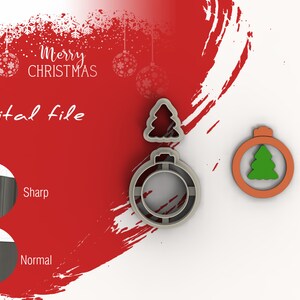 Puede incluir: Un conjunto de tres cortadores de galletas con forma de árbol de Navidad y un adorno navideño. El adorno tiene un árbol en su interior. Los cortadores están hechos de metal plateado. El fondo es rojo con copos de nieve blancos.