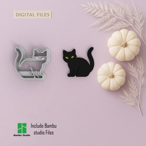 Pode incluir: Um recorte em forma de gato preto com olhos verdes e um cortador de biscoitos em forma de gato são exibidos ao lado de duas pequenas abóboras brancas e galhos decorativos em um fundo lavanda. O texto "DIGITAL FILES" está no topo.