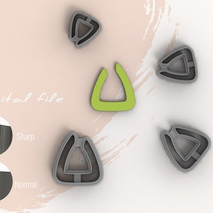 Puede incluir: Cuatro cortadores de galletas de forma triangular gris con un cortador de galletas de forma triangular verde en el centro. Los cortadores de galletas tienen una abertura en forma de U en el centro.