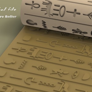 Op de afbeelding: Een bruine textuurroller met een herhalend patroon van oude Egyptische hiërogliefen. De roller is gedeeltelijk uitgerold, waardoor het patroon op het oppervlak eronder zichtbaar wordt.