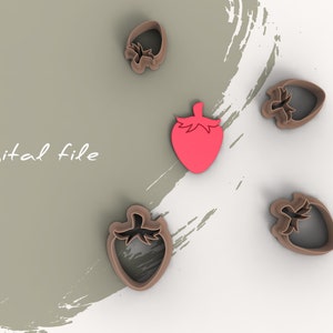 Puede incluir: Un conjunto de cortadores de galletas con forma de fresa y una sola forma de fresa roja. Los cortadores son marrones y la fresa es roja. Las palabras "Digital file" están escritas en cursiva.