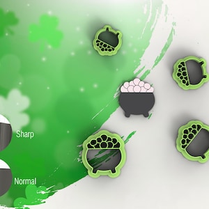 May include: Four green plastic cookie cutters shaped like a pot of gold with coins. The cutters are on a white background with a green and white abstract design.
