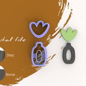 Puede incluir: Un conjunto de tres cortadores de galletas con forma de flor, botella y hoja. El cortador de flores es morado, el cortador de botellas es azul claro y el cortador de hojas es verde. Los cortadores están sobre un fondo marrón con una pincelada blanca.