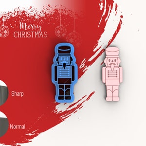 May include: Two nutcracker cookie cutters, one blue and one pink. The cutters are shown against a red and white background with the text "Merry Christmas".