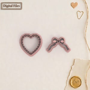 Può includere: Due formine rosa: un cuore con bordo smerlato e un fiocco. La formina a forma di cuore ha un contorno rosa scuro. La formina a forma di fiocco ha un contorno rosa scuro. Le parole "Digital Files" sono in una cornice rettangolare.