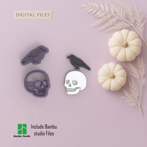 Op de afbeelding: Een digitale Halloween-bestandenset met een schedel, een raaf en twee pompoenen. De schedel en de raaf zijn donkergrijs. De pompoenen zijn wit. De tekst "DIGITAL FILES" staat bovenaan. De tekst "Include Bambu studio Files" staat onderaan.