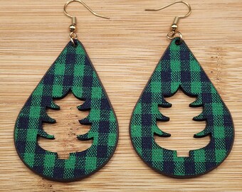 May include: A pair of green and black plaid teardrop-shaped earrings with a cut-out tree design.
