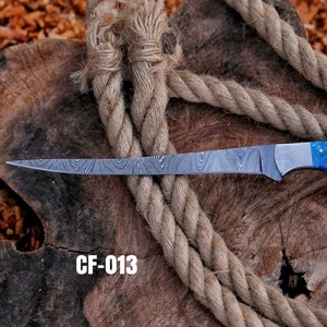 May include: A long, patterned steel knife with a blue handle, resting on a wooden surface with a thick rope. The blade has a unique wave-like pattern. The text "CF-013" is displayed in white.