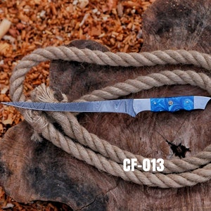 May include: A Damascus steel fillet knife with a blue and white handle, resting on a wooden surface with a coiled rope. The knife has a long, thin blade and the text "CF-013" is visible.