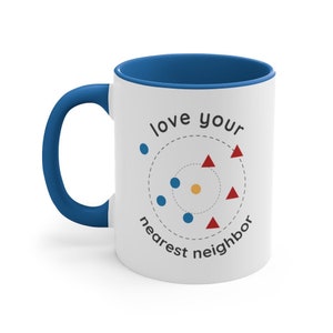May include: White ceramic coffee mug with a blue rim and handle. The mug has a graphic of a circle with blue dots and red triangles around it. The text "love your nearest neighbor" is written around the circle.