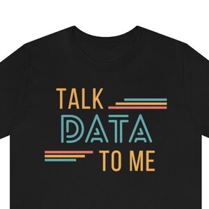 May include: Black t-shirt with the text "TALK DATA TO ME" in a retro font with colorful stripes.