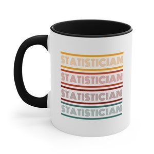May include: White ceramic coffee mug with a black rim and handle. The mug has a design of the word "STATISTICIAN" repeated four times in a retro style with different colored stripes.