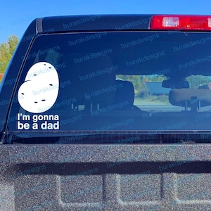 May include: White vinyl car sticker with a sperm cell design and the words "I'm gonna be a dad". The sticker is on the rear window of a black vehicle.