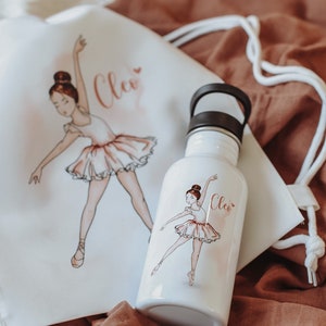 Puede incluir: Una bolsa de cordón blanco y una botella de agua blanca con tapa negra. Ambos artículos presentan una ilustración de bailarina y el nombre "Cleo" en letras rosas.