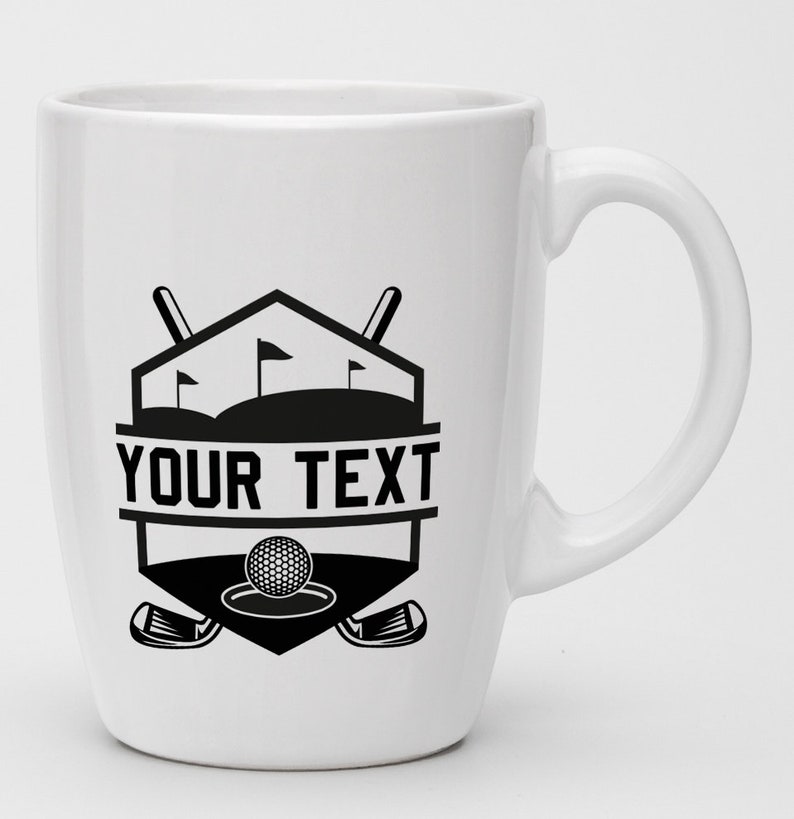 May include: White ceramic coffee mug with a black and white golf-themed design. The design features a golf ball, golf clubs, and a golf course with flags. The text "YOUR TEXT" is printed on the mug.