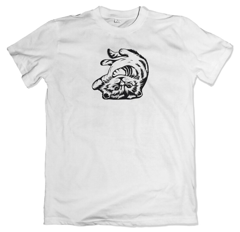 May include: White t-shirt with a black and white illustration of a cat upside down.