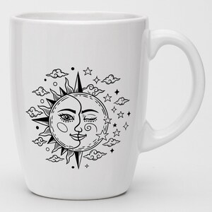 Puede incluir: Taza de cer&aacute;mica blanca con una ilustraci&oacute;n en blanco y negro de un sol y una luna con un ojo gui&ntilde;ando y una boca sonriente. El sol y la luna est&aacute;n rodeados de nubes y estrellas.