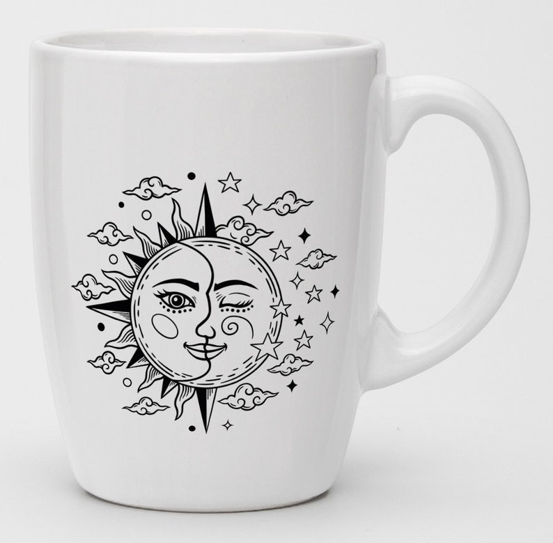 Puede incluir: Taza de cer&aacute;mica blanca con una ilustraci&oacute;n en blanco y negro de un sol y una luna con un ojo gui&ntilde;ando y una boca sonriente. El sol y la luna est&aacute;n rodeados de nubes y estrellas.