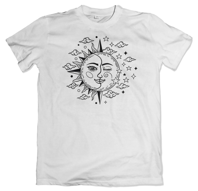 Puede incluir: Camiseta blanca con un gr&aacute;fico en blanco y negro de un sol y una luna con un ojo gui&ntilde;ando, nubes y estrellas.