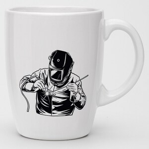 May include: White ceramic mug with a black and white illustration of a welder wearing a welding mask and holding a welding torch.
