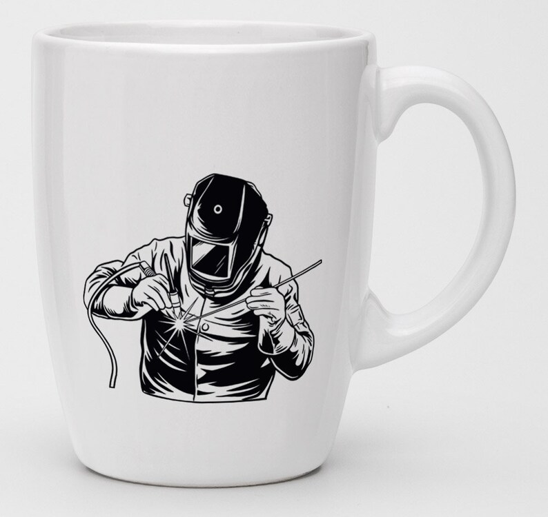 May include: White ceramic mug with a black and white illustration of a welder wearing a welding mask and holding a welding torch.