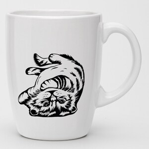 May include: White ceramic mug with a black and white illustration of a cat upside down. The cat is looking up with its paws in the air.