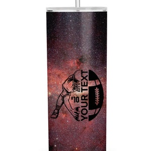 May include: A black and white illustration of a football player holding a football with the text "YOUR TEXT" on a red and black galaxy print tumbler.