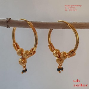 Peut inclure: Boucles d'oreilles créoles en or avec trois petites perles dorées et des perles noires qui pendent du bas. Les créoles mesurent 30 mm de long et 25 mm de large. Le texte "kapa-jewellery" est écrit dans le coin supérieur droit de l'image. Le texte "uk seller" est écrit dans le coin inférieur droit de l'image.