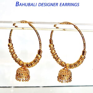 Peut inclure: Une paire de boucles d'oreilles créoles dorées avec un pendentif en forme de cloche. Les boucles d'oreilles sont faites de petites perles rondes et ont une finition texturée.