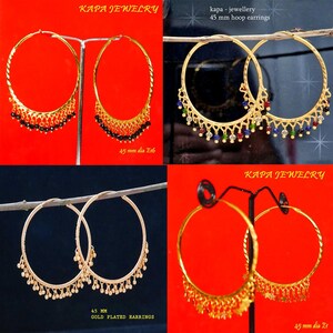 Op de afbeelding: Vier paar gouden creolen met decoratieve bedels die eronder hangen. De oorbellen worden gepresenteerd op een rode achtergrond met de tekst "KAPA JEWELRY" en "45 mm dia Et" in zwart.
