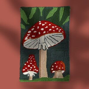 May include: A rug with a green and blue background featuring three red and white mushrooms. The largest mushroom has a white stem and the two smaller mushrooms have brown stems.