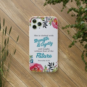 May include: A white phone case with a floral design and the text "She is clothed with Strength & Dignity and laughs without fear of the Future Proverbs 31:25".