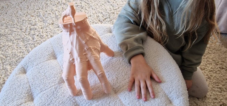 Op de afbeelding: Een 3D-geprint handbeeld met een realistisch, gedetailleerd ontwerp. De hand is geposeerd met gestrekte vingers en lijkt gemaakt te zijn van lichtroze materiaal.