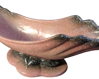 May include: A pink and black ceramic planter shaped like a leaf with a speckled glaze.