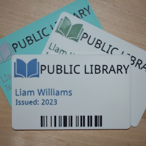 May include: White library card with a blue book icon, the text "PUBLIC LIBRARY", and the name "Liam Williams" with the date "Issued: 2023". The card has a black barcode.