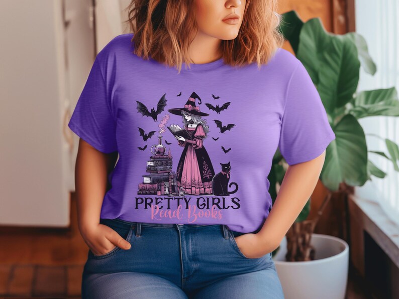May include: A purple t-shirt featuring a witch reading a book, surrounded by bats and a black cat. The text "PRETTY GIRLS Read Books" is below the illustration. The shirt is worn with blue jeans.